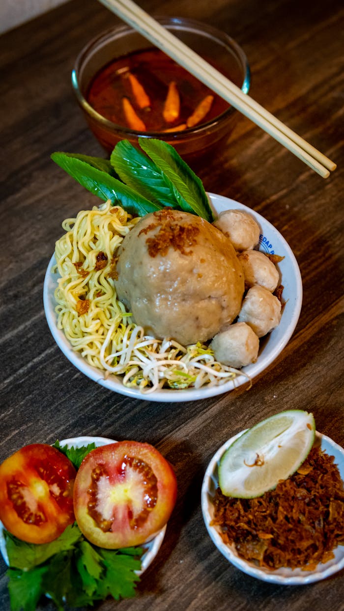 team-03 Close-up of a traditional Indonesian bakso noodle meal with fresh ingredients.